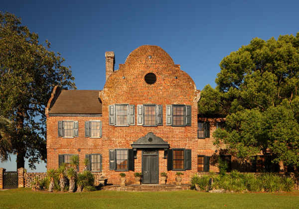 The Middleton Place plantation house, with its original brick structure, sits nestled between two oak trees