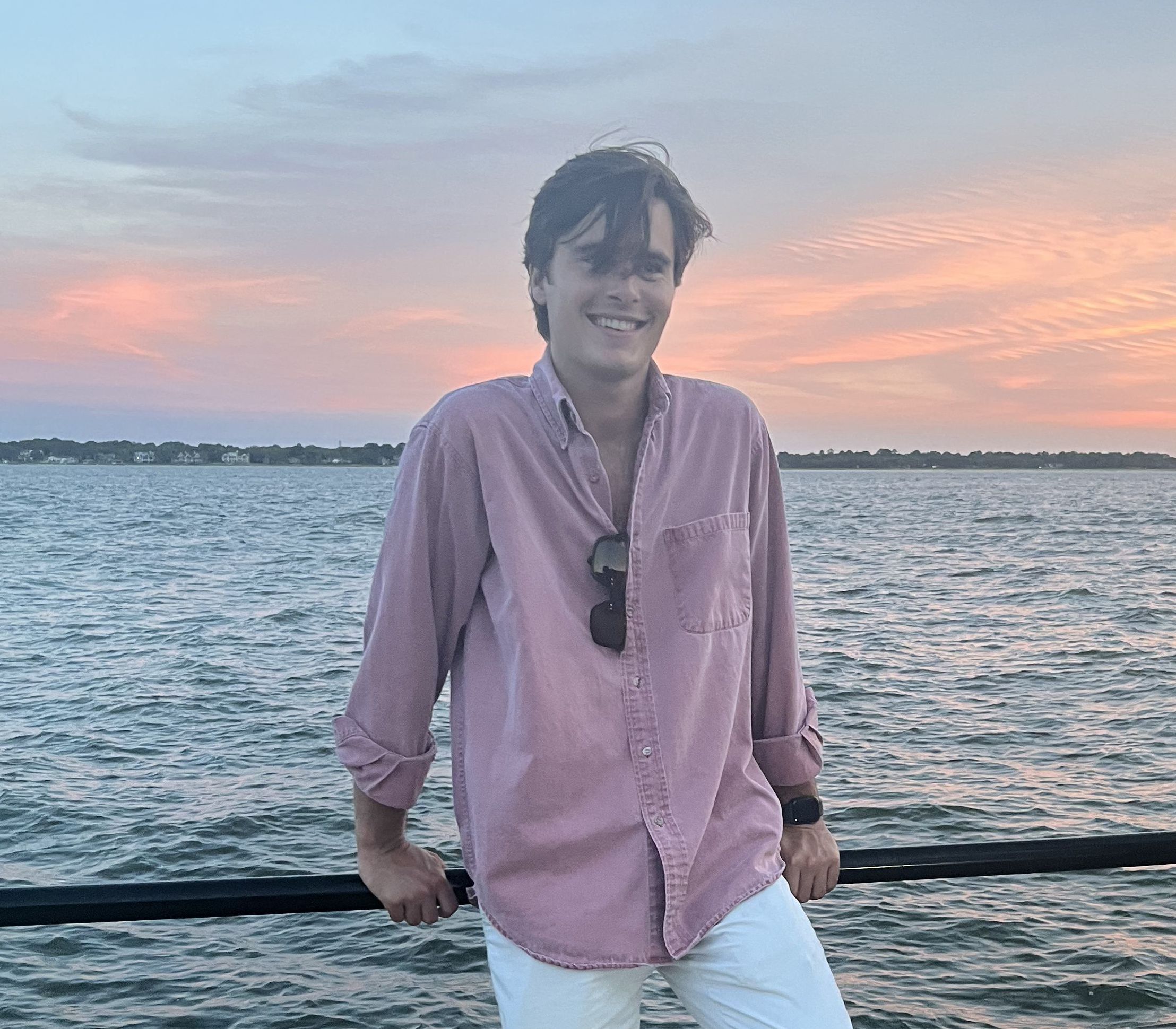 A photograph of tour guide, Thomas Pritchard, standing in front of Charleston Harbor with the sunset in the background